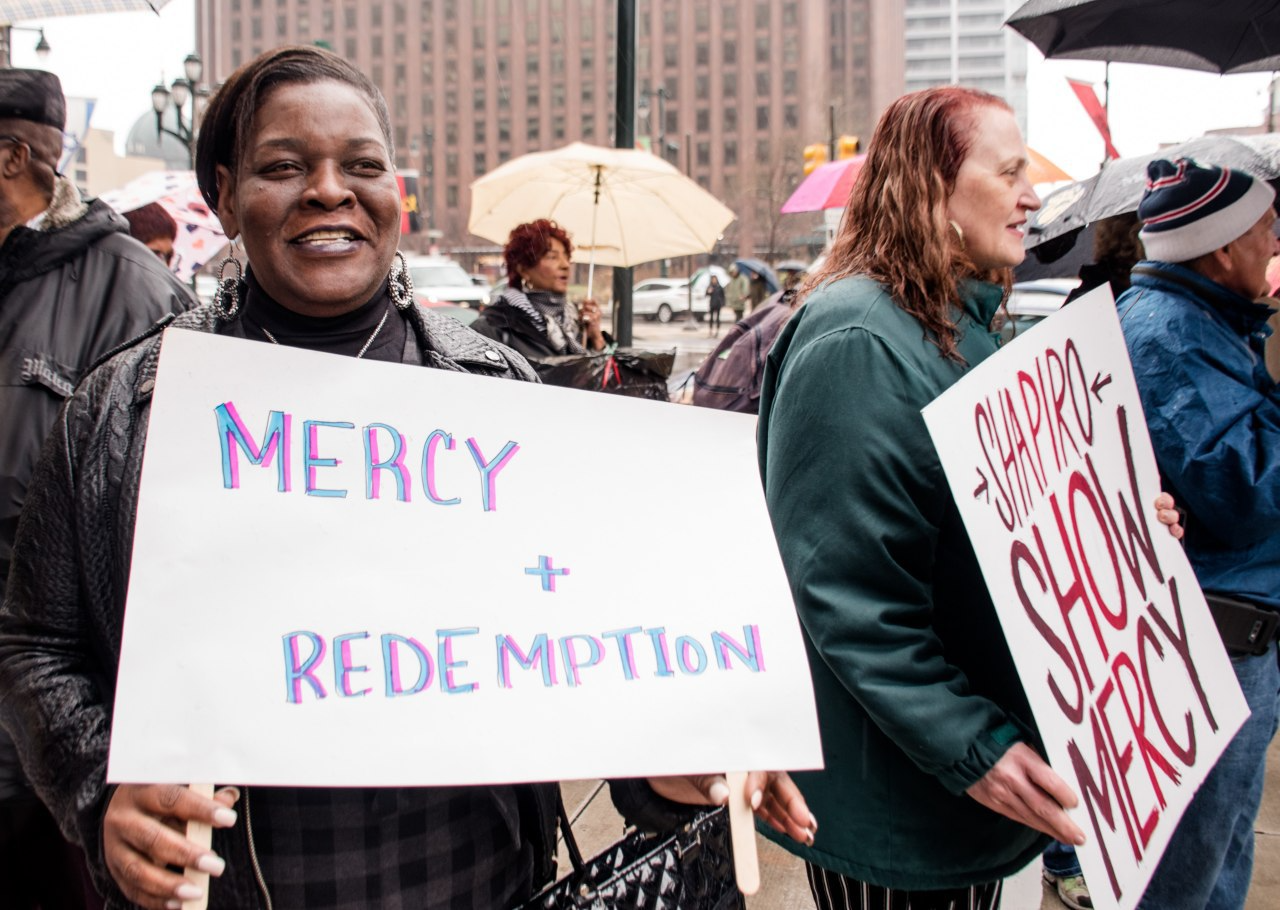 Marthea Brown holds a sign that says Mercy and Redemption