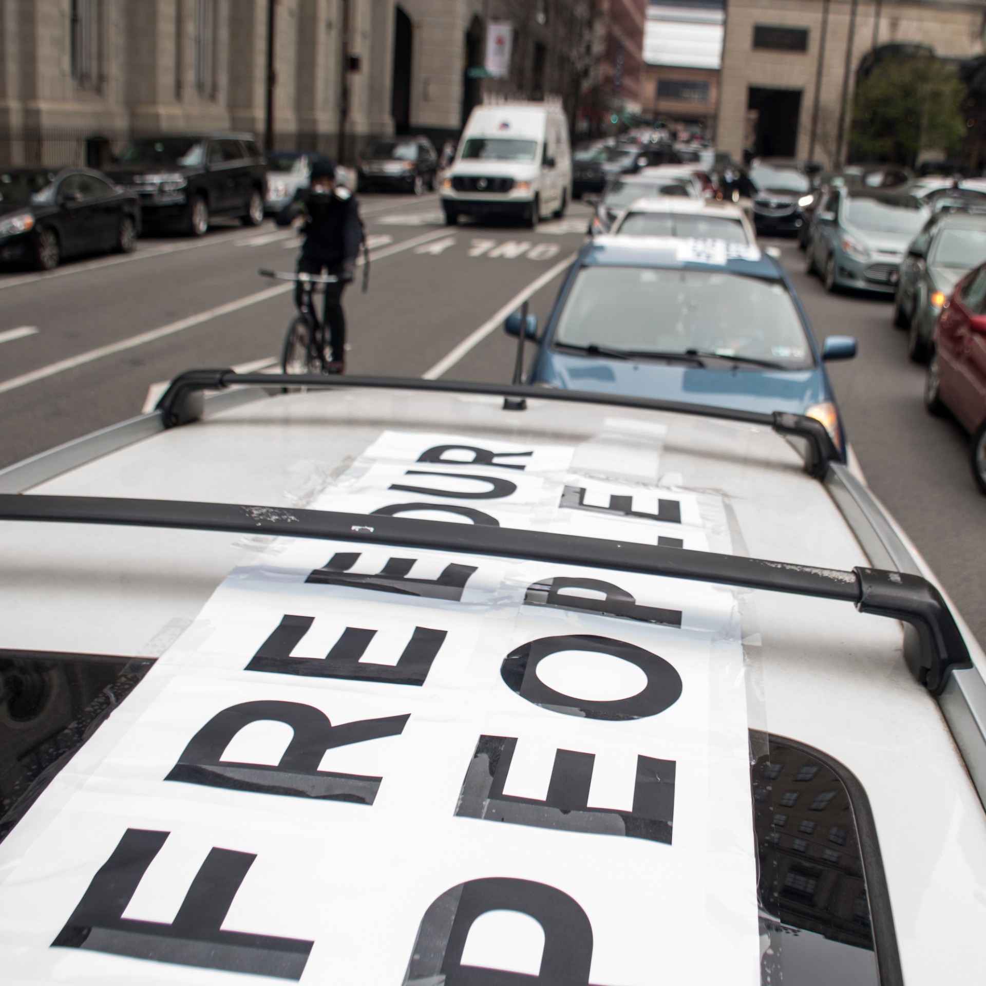 A sign on top of a car reads Free Our People at a car caravan protest